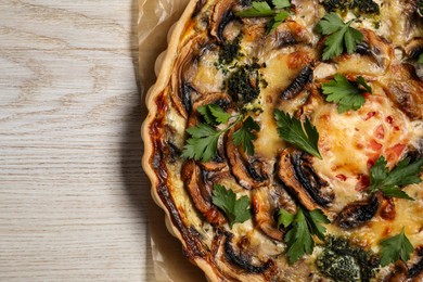 Delicious quiche with mushrooms and parsley on white wooden table, top view. Space for text