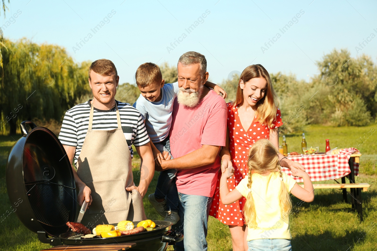 Photo of Happy family having barbecue in park on sunny day