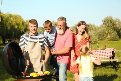 Photo of Happy family having barbecue in park on sunny day