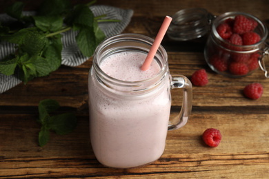 Photo of Tasty milk shake with raspberries and mint on wooden table