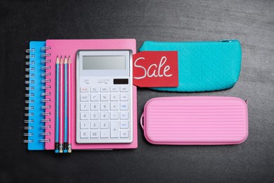 Photo of Flat lay composition with school stationery and word Sale on blackboard
