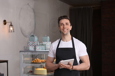 Photo of Young waiter with tablet computer at workplace