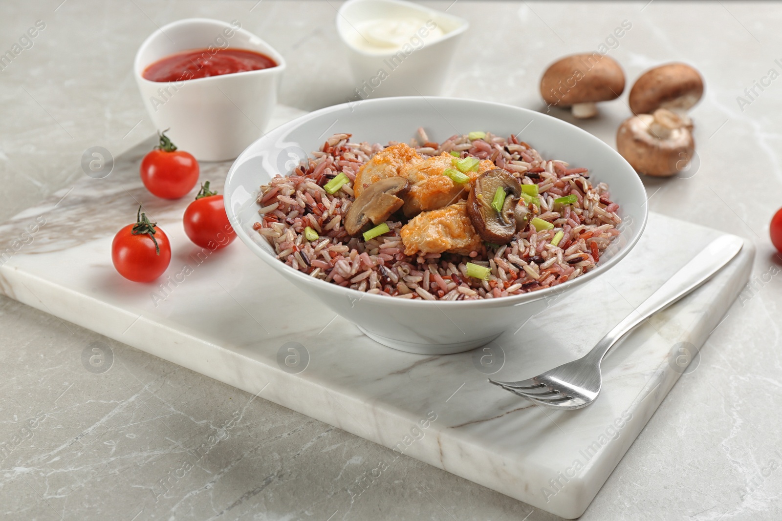 Photo of Tasty brown rice with chicken and mushrooms on light grey marble table