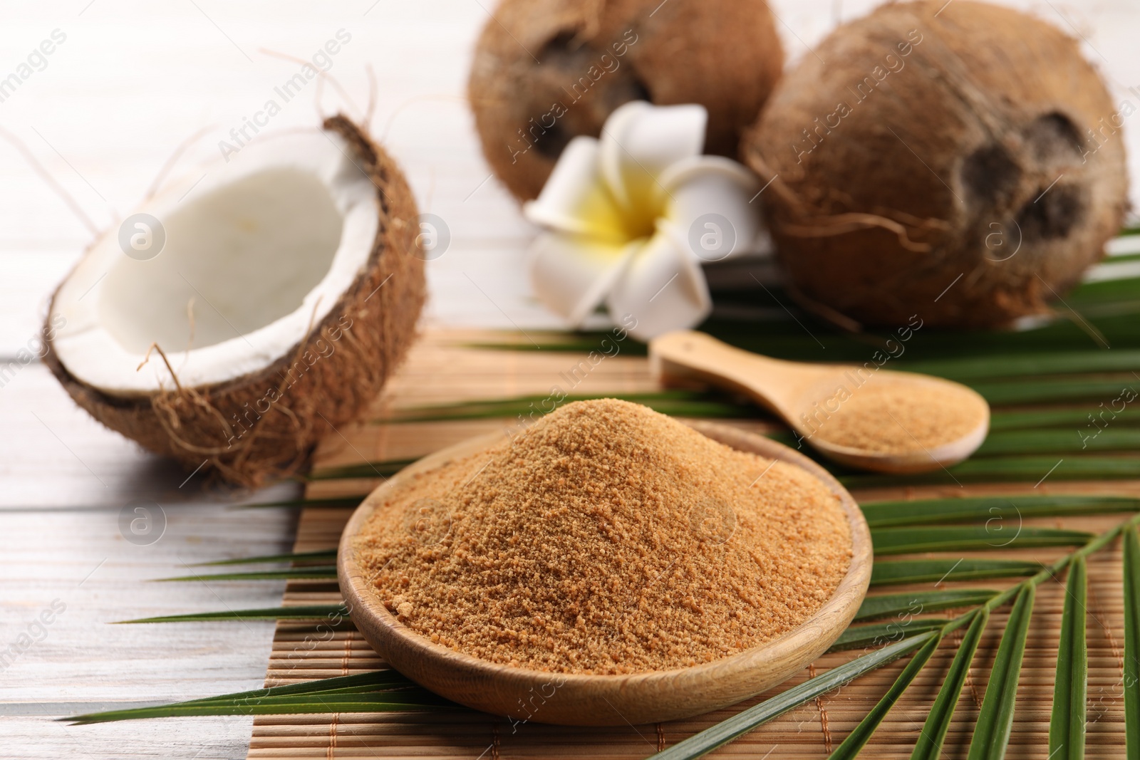 Photo of Coconut sugar, palm leaves, fruits and bamboo mat on wooden rustic table, closeup