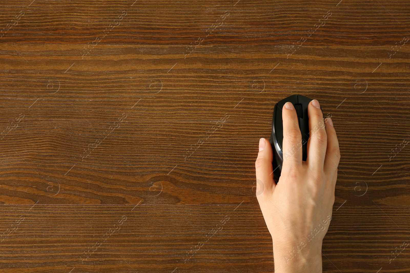 Photo of Woman using computer mouse on wooden background, top view. Space for text