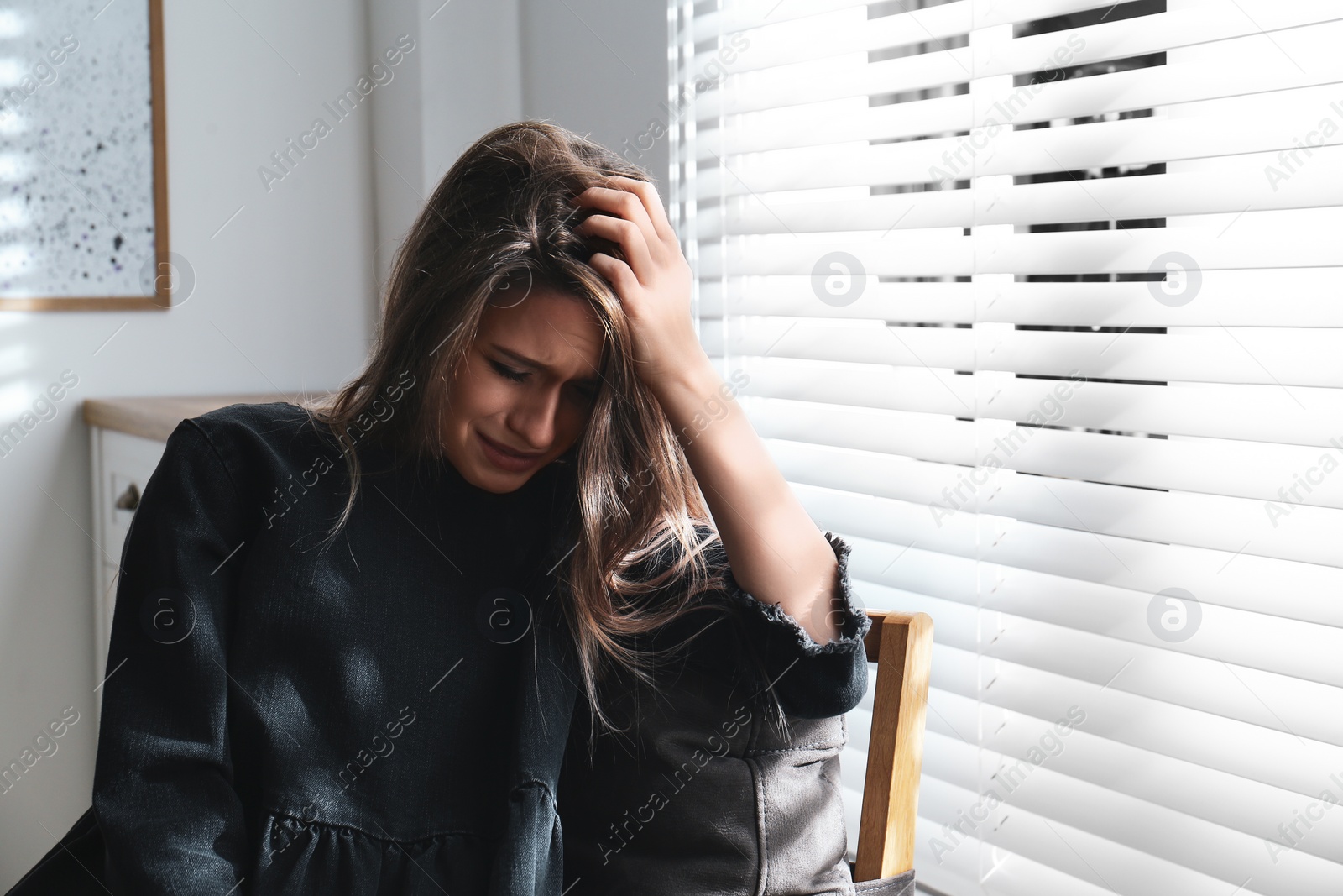 Photo of Abused young woman crying indoors. Domestic violence concept