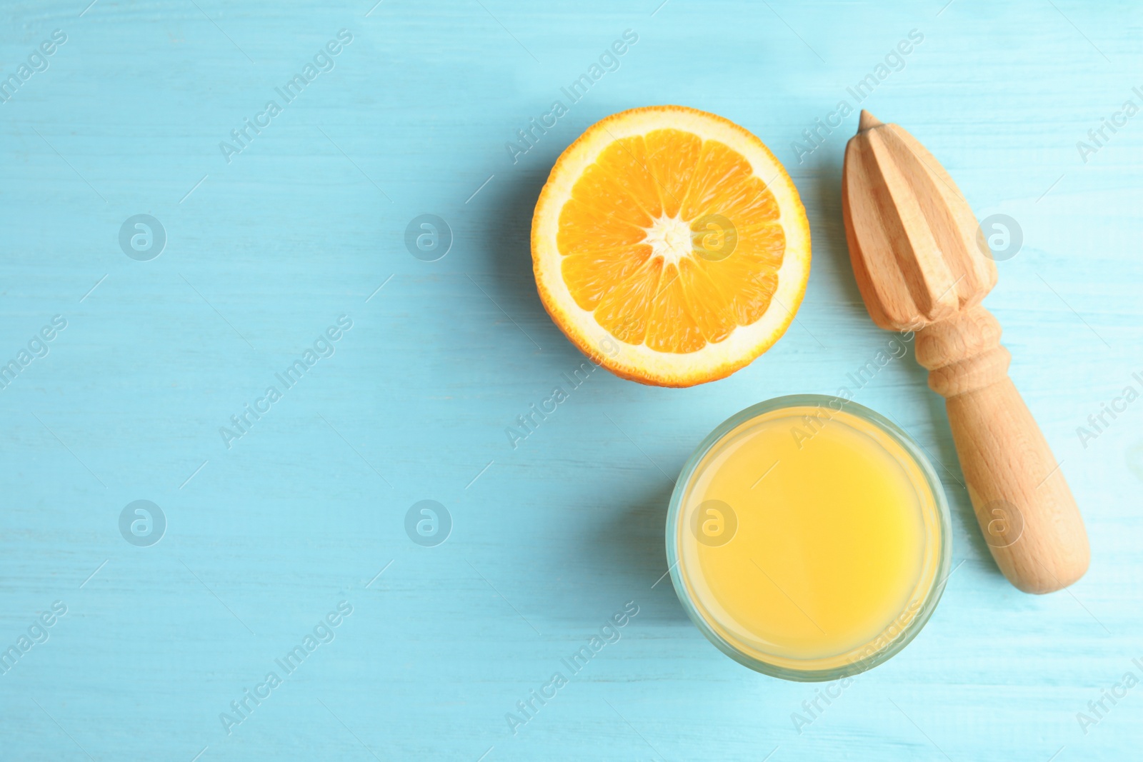 Photo of Orange juice, reamer and cut fruit on wooden background, flat lay with space for text