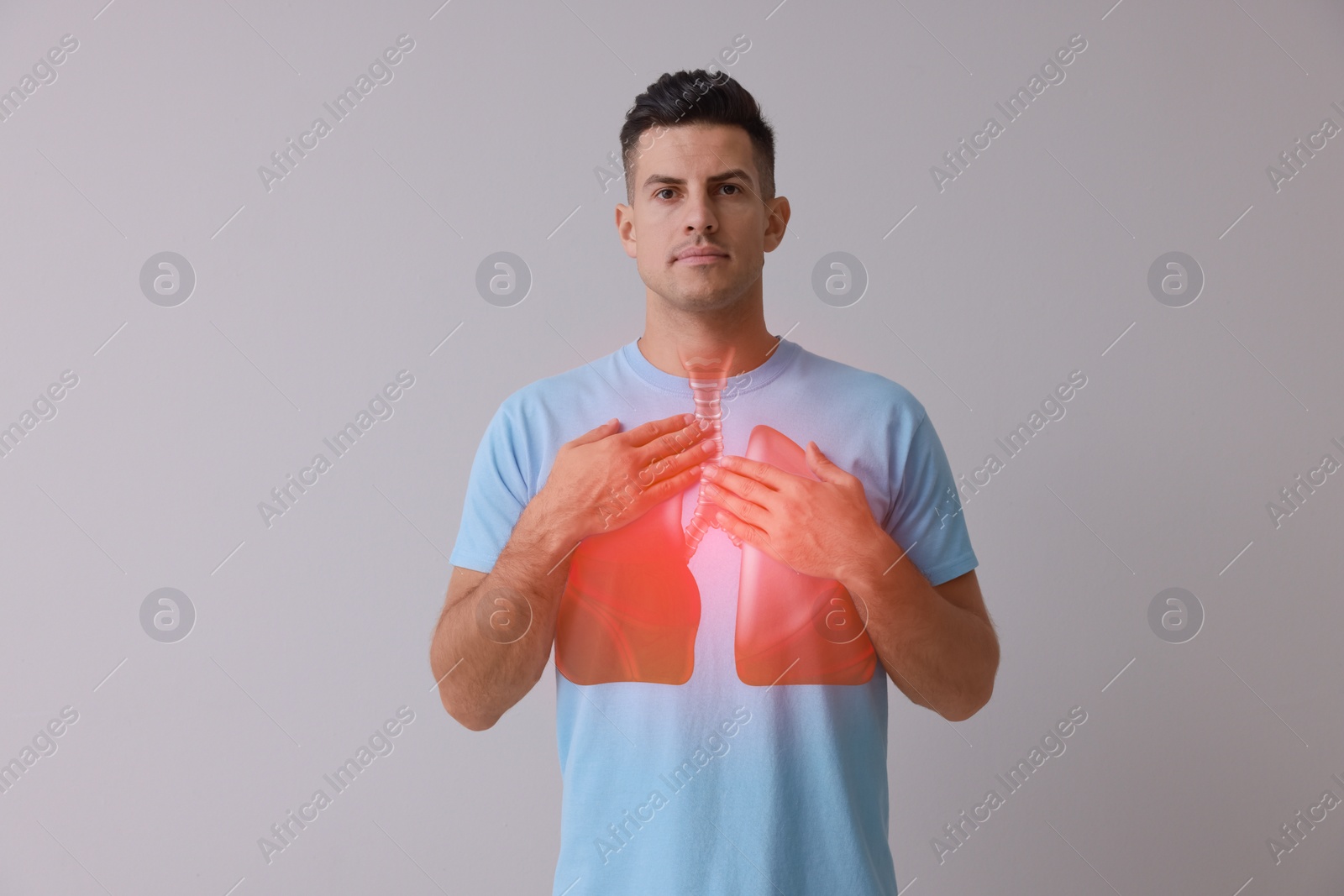 Image of Handsome man holding hands near chest with illustration of lungs on grey background
