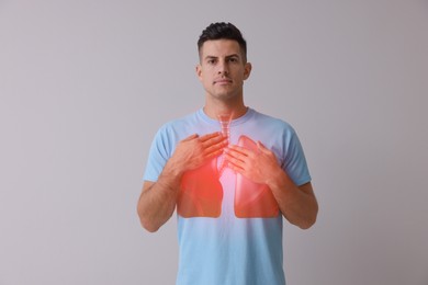 Handsome man holding hands near chest with illustration of lungs on grey background