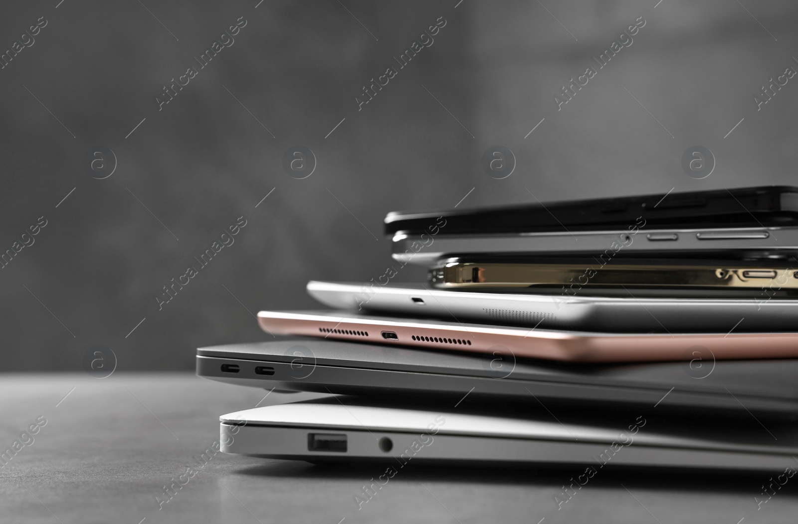 Photo of Many different modern gadgets on grey table, closeup. Space for text