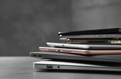 Photo of Many different modern gadgets on grey table, closeup. Space for text