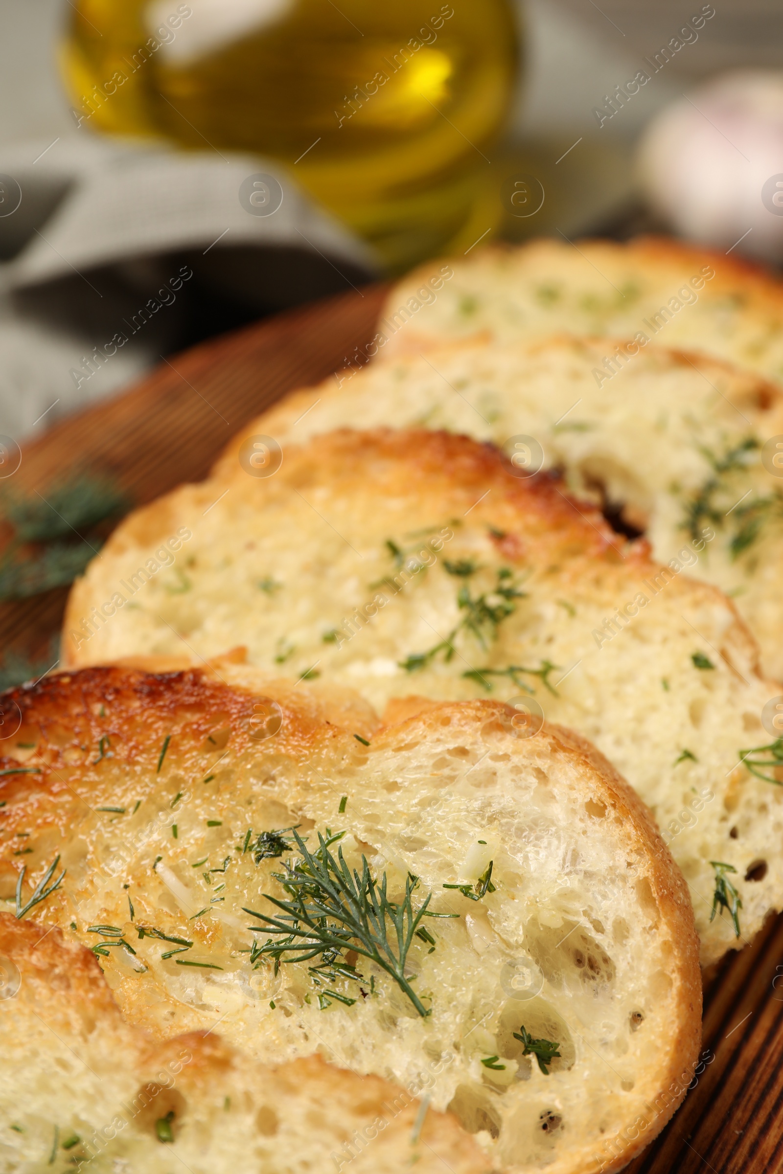 Photo of Tasty baguette with garlic and dill on wooden tray, closeup