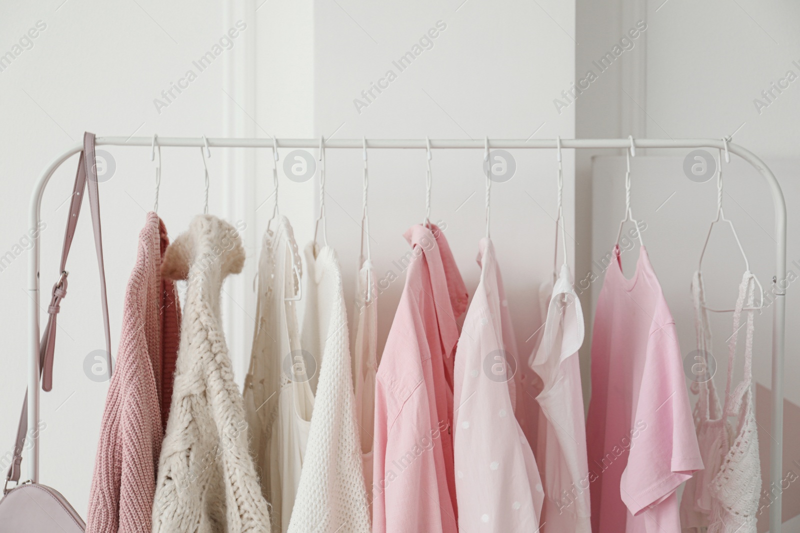 Photo of Rack with stylish clothes near white wall, closeup