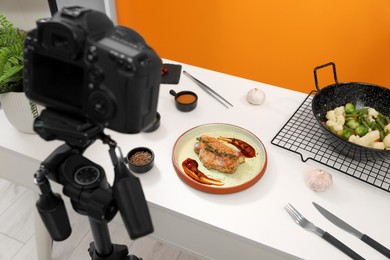 Photo of Professional camera on tripod and composition with delicious meat medallion in studio. Food photography
