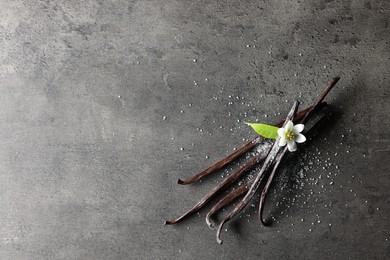 Photo of Vanilla pods, leaf and flower on grey textured table, top view. Space for text
