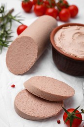 Photo of Delicious liver sausage, paste and other products on white tiled table, closeup