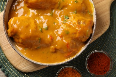 Photo of Tasty chicken curry and spices on green place mat, flat lay
