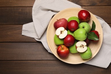 Photo of Plate with fresh ripe apples and leaves on wooden table, top view. Space for text