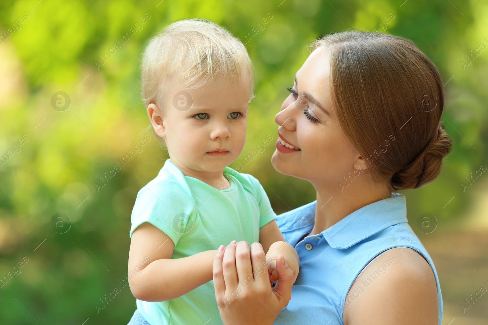 Photo of Young mother with her cute child in green park