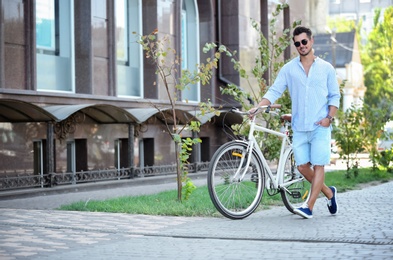 Photo of Handsome young hipster man with bicycle outdoors
