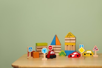 Photo of Set of different wooden toys on table near olive wall, space for text. Children's development