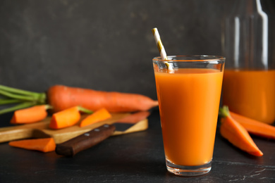 Photo of Glass of freshly made carrot juice on black table