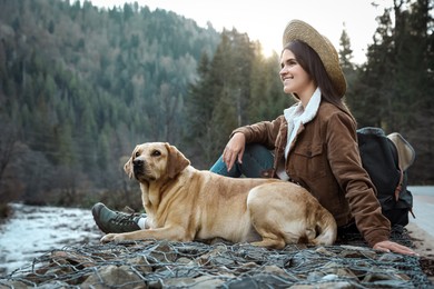 Photo of Happy woman and adorable dog in mountains. Traveling with pet