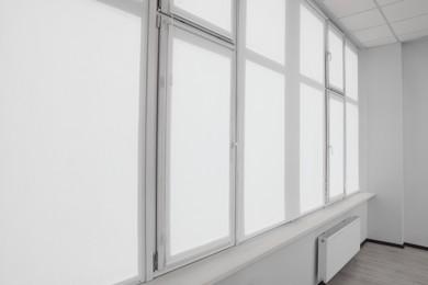 Photo of Window with closed white roller blinds indoors