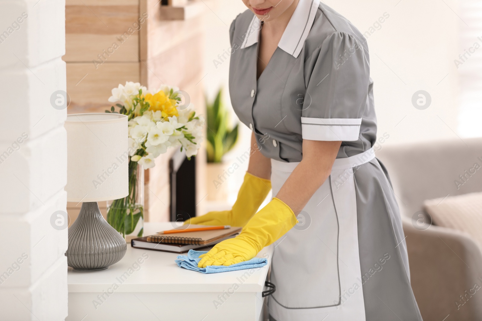 Young chambermaid wiping dust from furniture in hotel room, closeup Photo of Young chambermaid wiping dust from furniture in hotel room, closeup