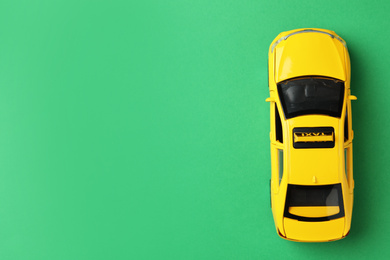 Photo of Yellow taxi car model on green background, top view. Space for text