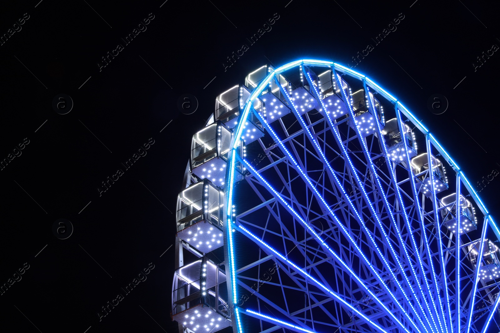 Photo of Beautiful glowing Ferris wheel against dark sky, low angle view