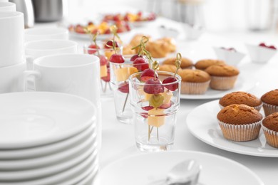 Photo of Table with different delicious snacks and dishware indoors. Coffee break