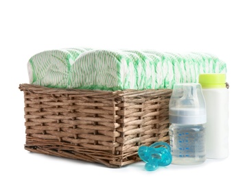 Photo of Basket with diapers and baby accessories on white background