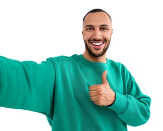 Photo of Smiling young man taking selfie and showing thumbs up on white background