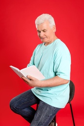 Photo of Senior man reading book on color background