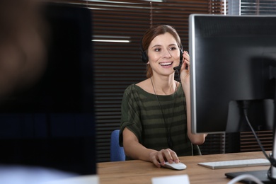 Photo of Female technical support operator with headset at workplace