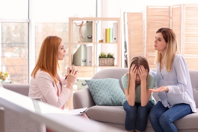 Photo of Young female psychologist working with teenage girl and her mother in office