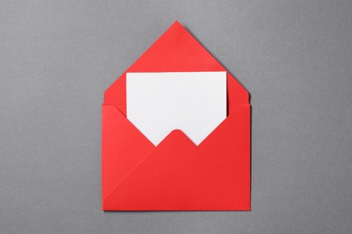 Photo of Blank sheet of paper in open letter envelope on grey background, top view