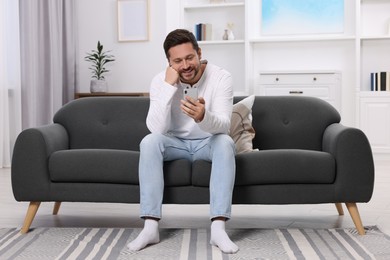 Photo of Happy man having video chat via smartphone at home