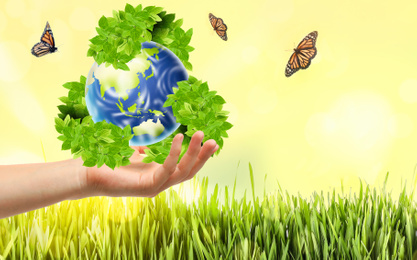 Image of Man with illustration of Earth and recycling symbol in hand, closeup