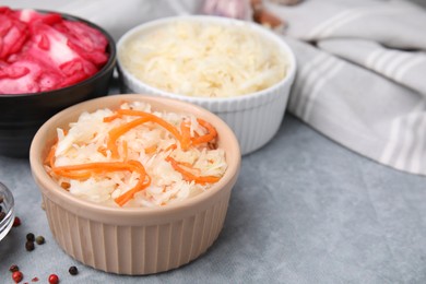 Photo of Delicious sauerkraut prepared according to different recipes on light gray table, closeup
