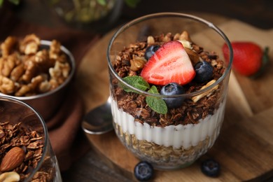 Photo of Tasty granola with berries, nuts and yogurt in glass on table, closeup