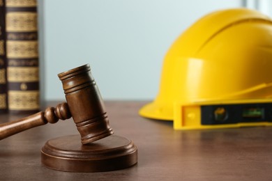 Photo of Construction and land law concepts. Judge gavel, books, level with hardhat on grey table, space for text