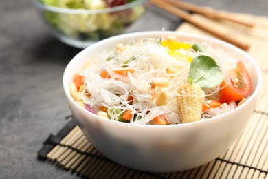 Photo of Tasty cooked rice noodles with vegetables on grey table