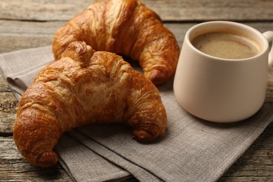 Photo of Delicious fresh croissants and cup of coffee on table, closeup