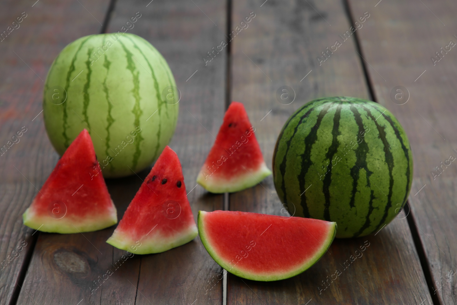 Photo of Different delicious ripe watermelons on wooden table