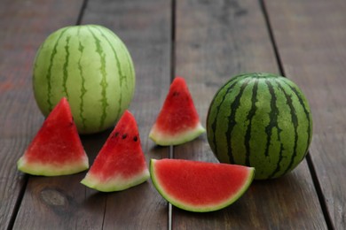 Photo of Different delicious ripe watermelons on wooden table