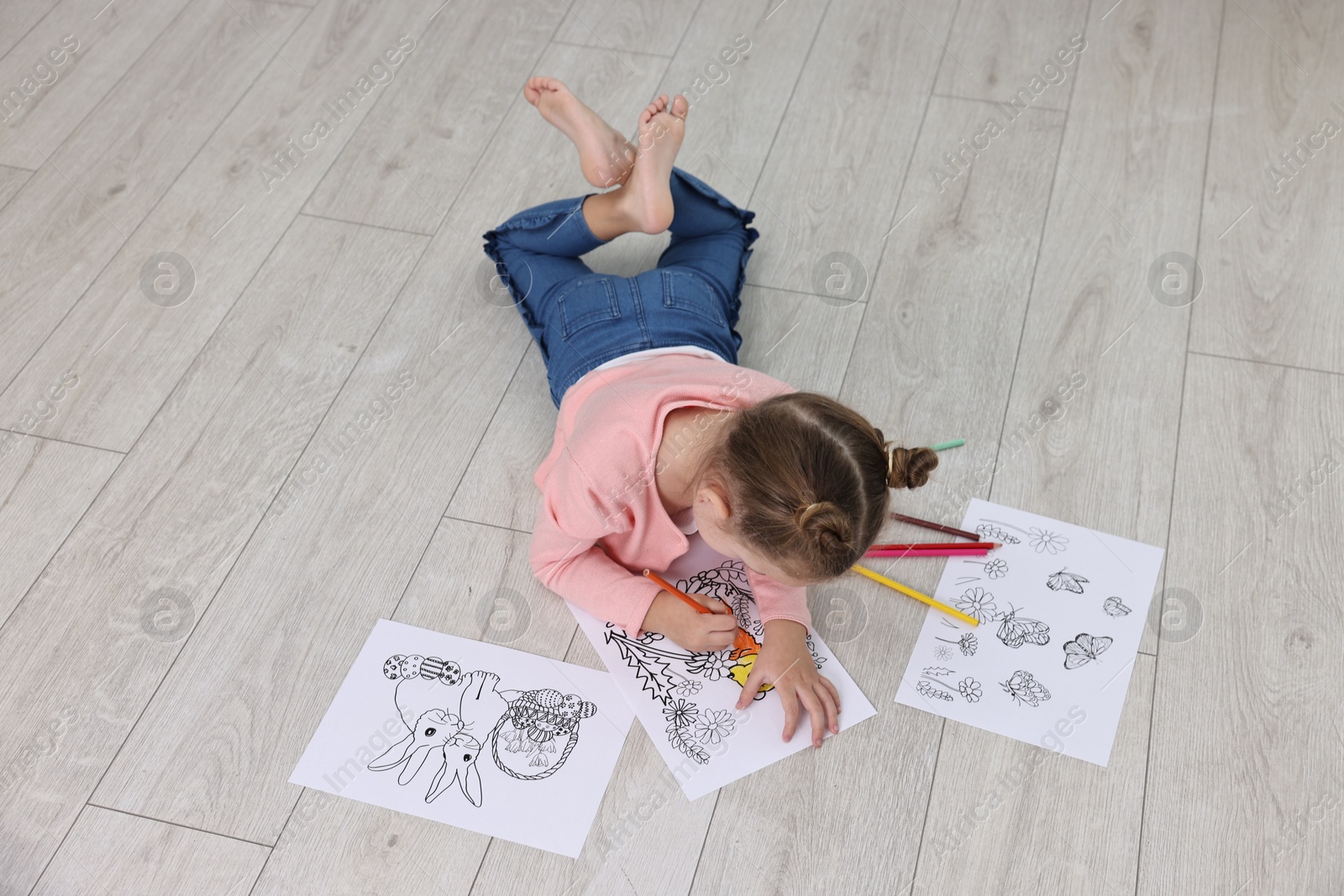 Photo of Little girl coloring on warm floor indoors. Heating system