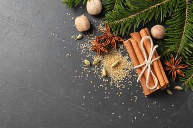 Different spices, nuts and fir branches on gray table, flat lay. Space for text