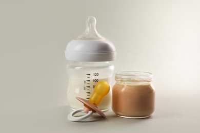 Photo of Healthy baby food, bottle of milk and pacifier on white background